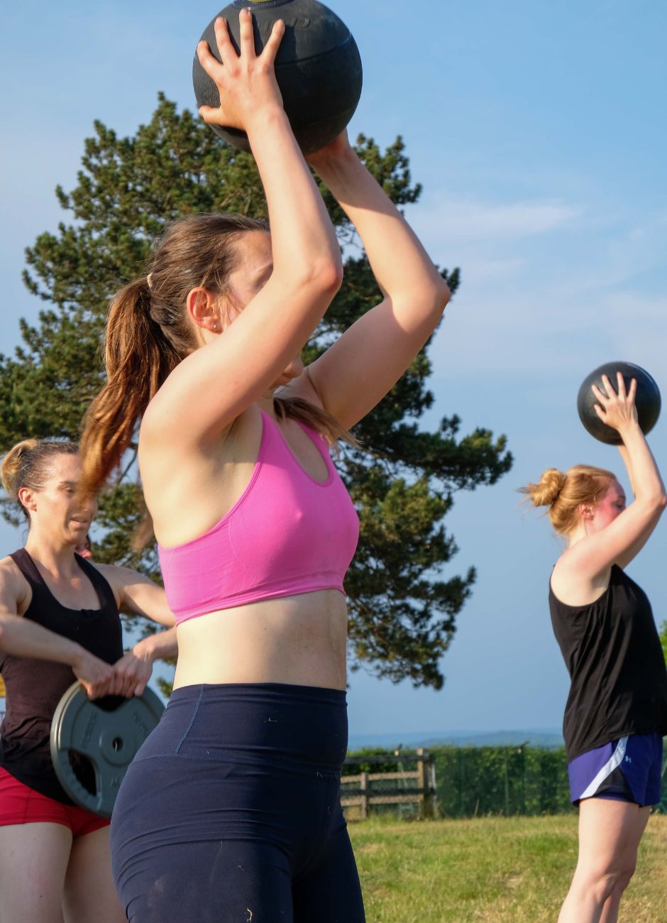 strong women at bootcamp with medicine balls and weight plates