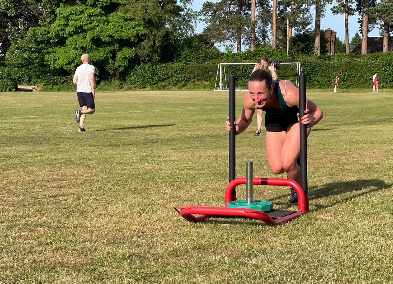 Woman pushing sled with weights, in recreation ground