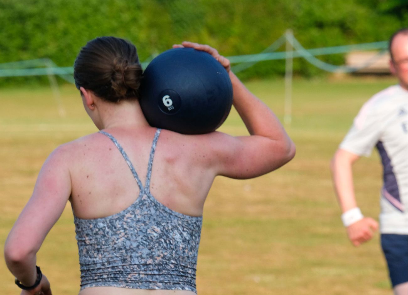 Woman running with slam ball in recreation ground