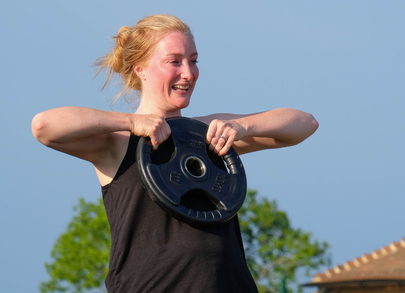 Smiling woman with weight plate exercising