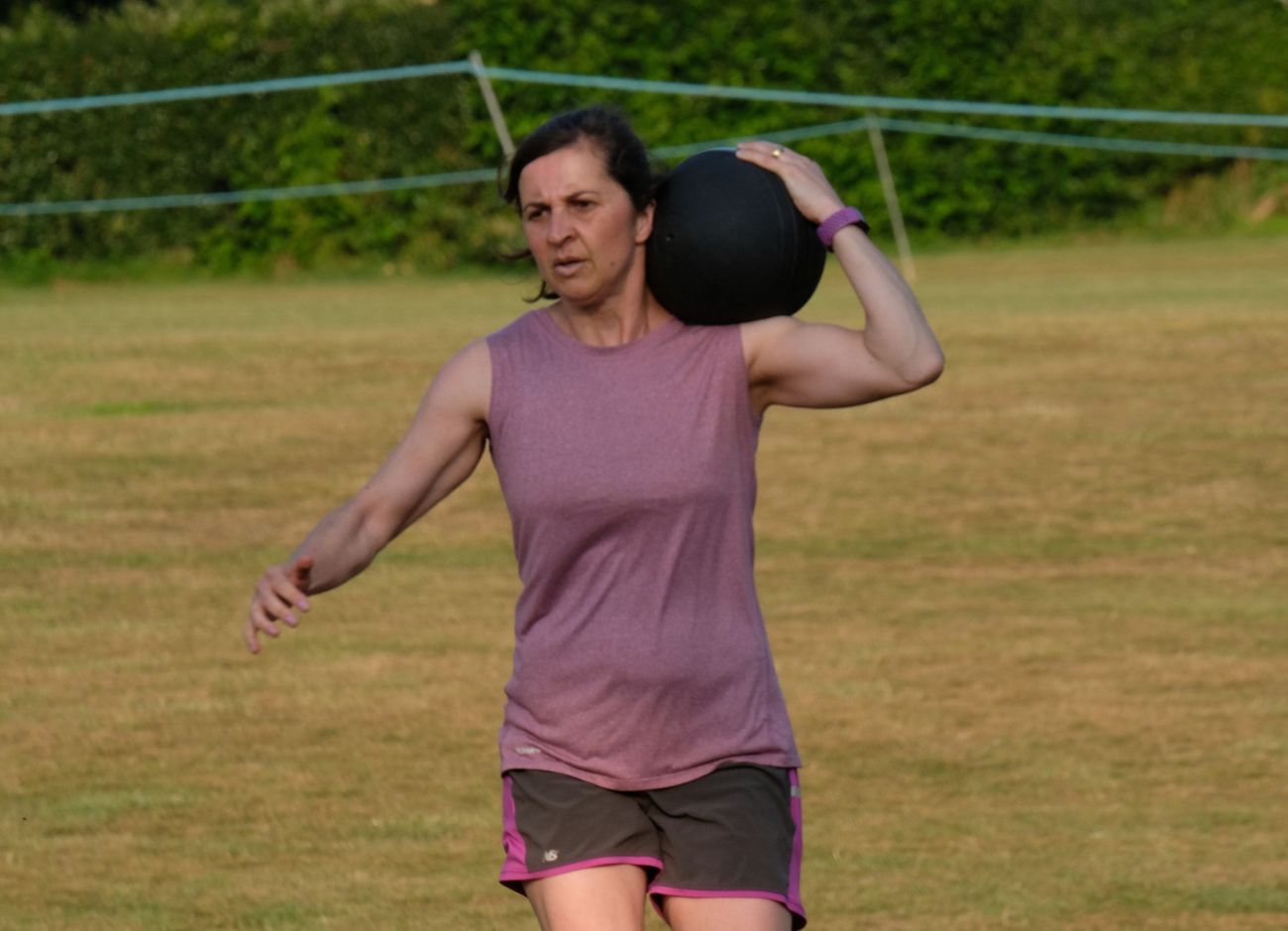 strong woman running with medicine ball at bootcamp