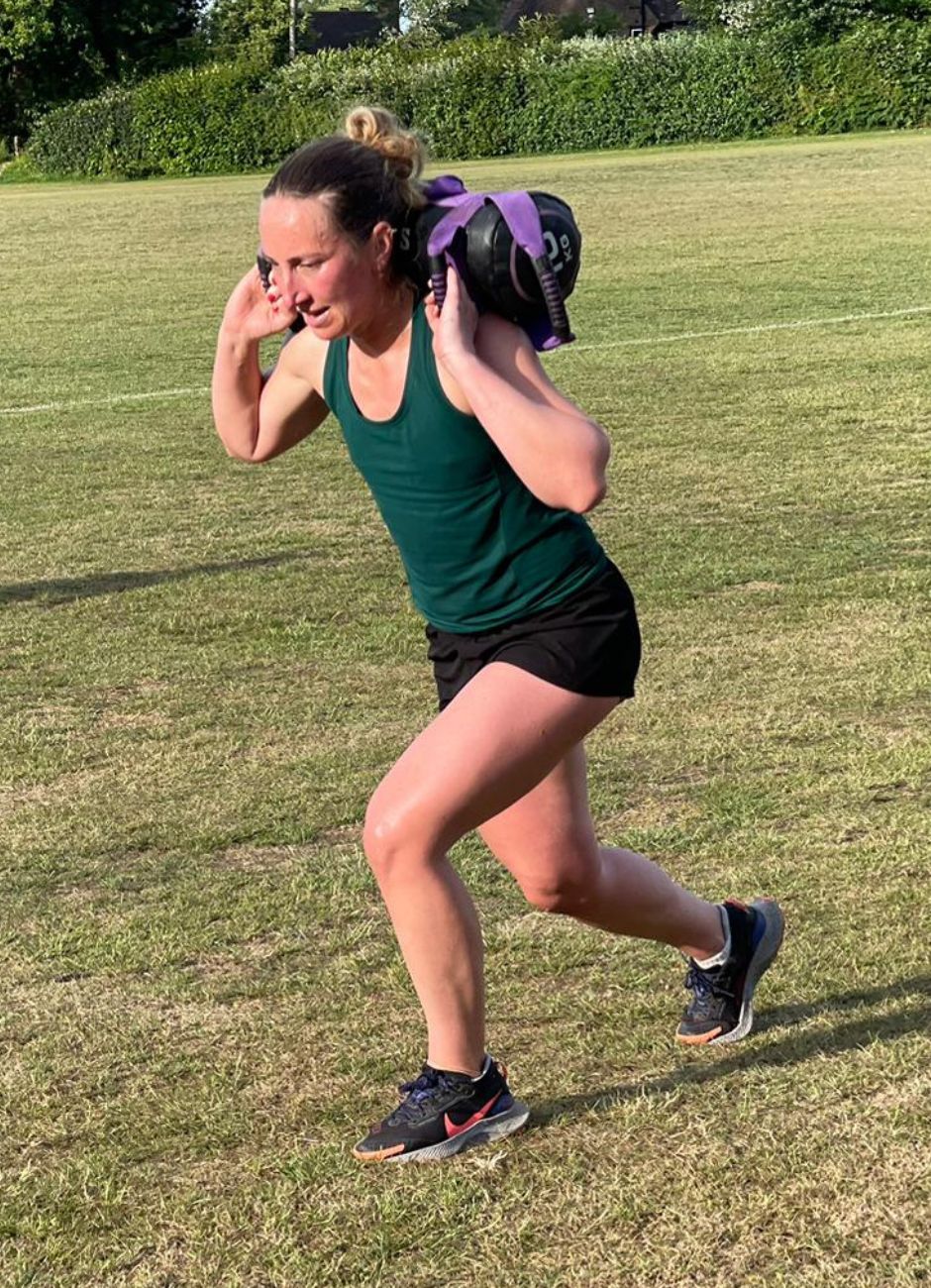 strong woman with weighted bag doing lunges